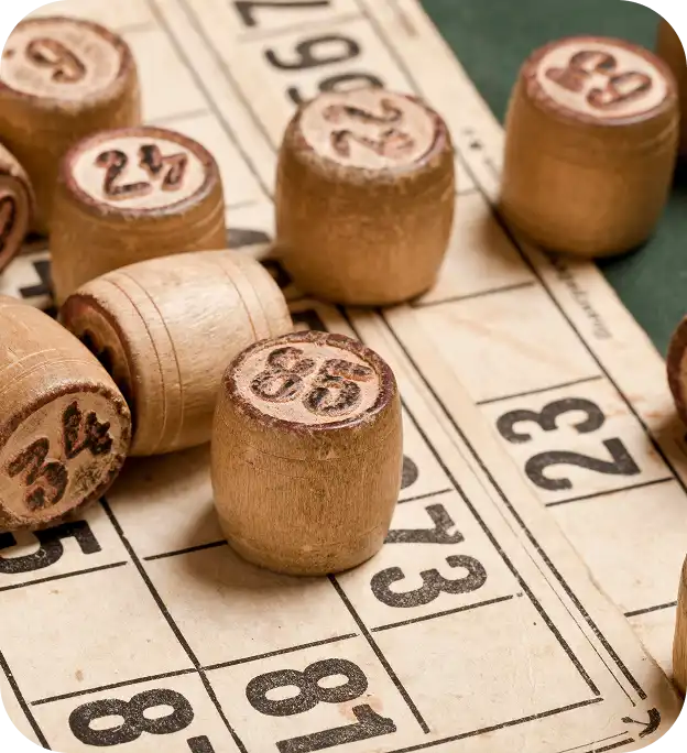 Detailní záběr na bingo desku s barevnými čísly a dřevěnými kostkami rozházenými po celé ploše.